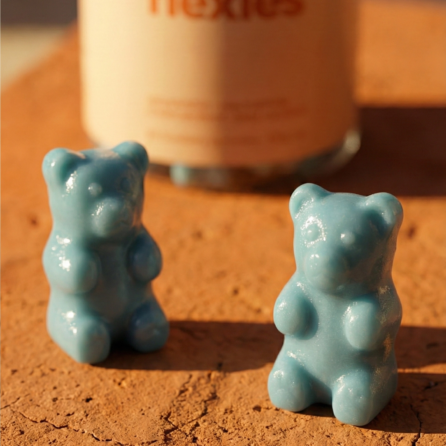Close-up of teal tanning gummies with bottle in background