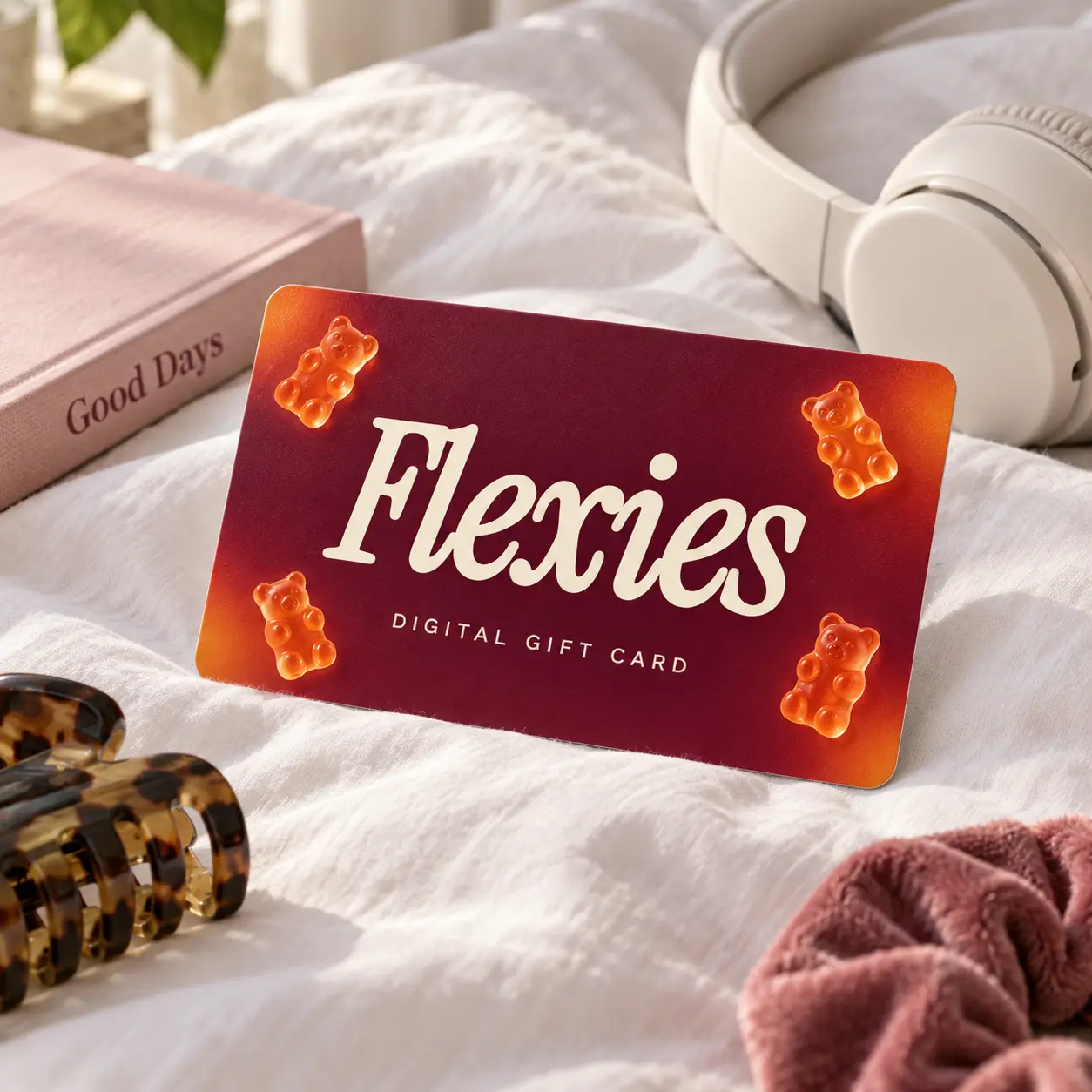 Flexies digital gift card styled on bed linen with a book, headphones and claw clip