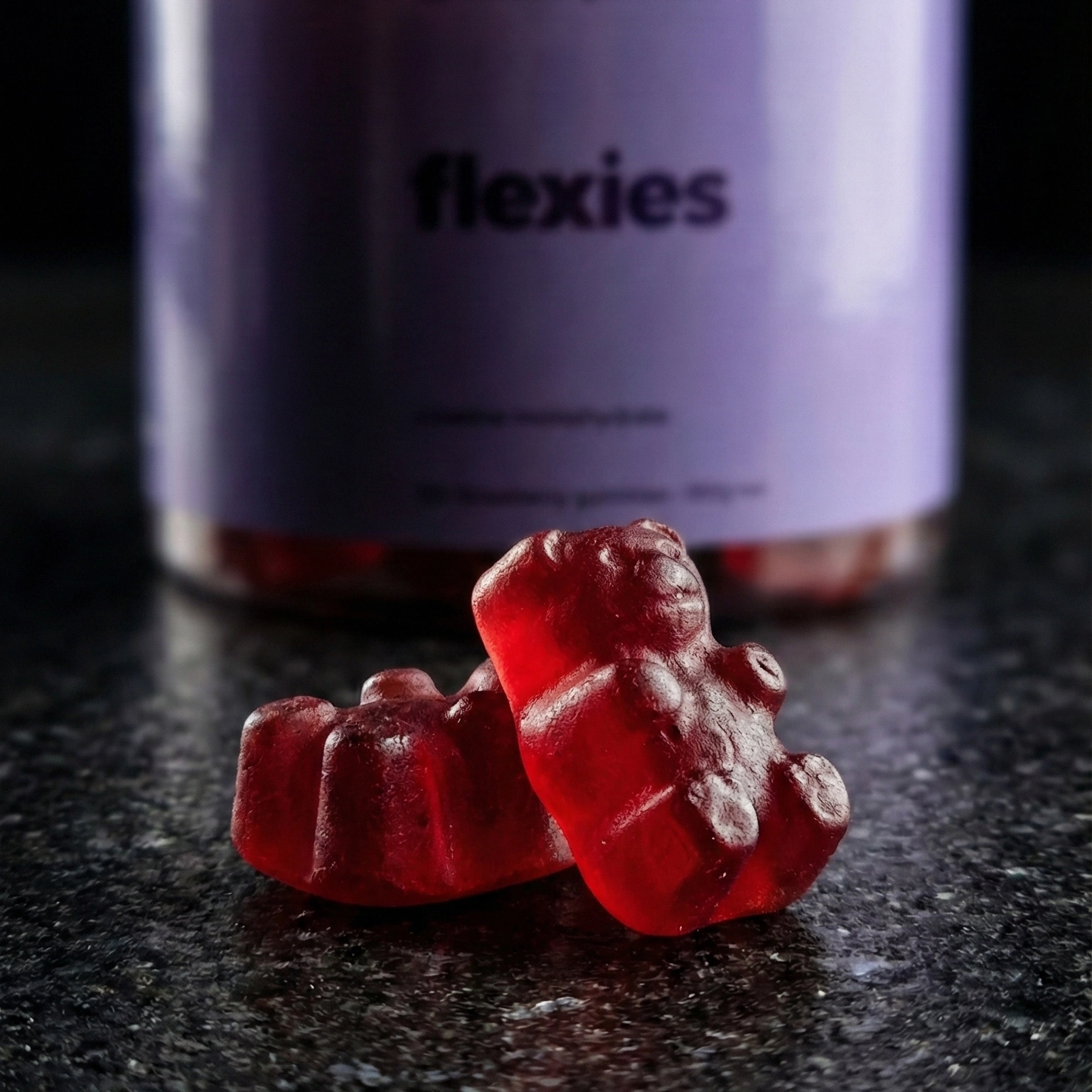 Close-up of red creatine gummies with bottle in background