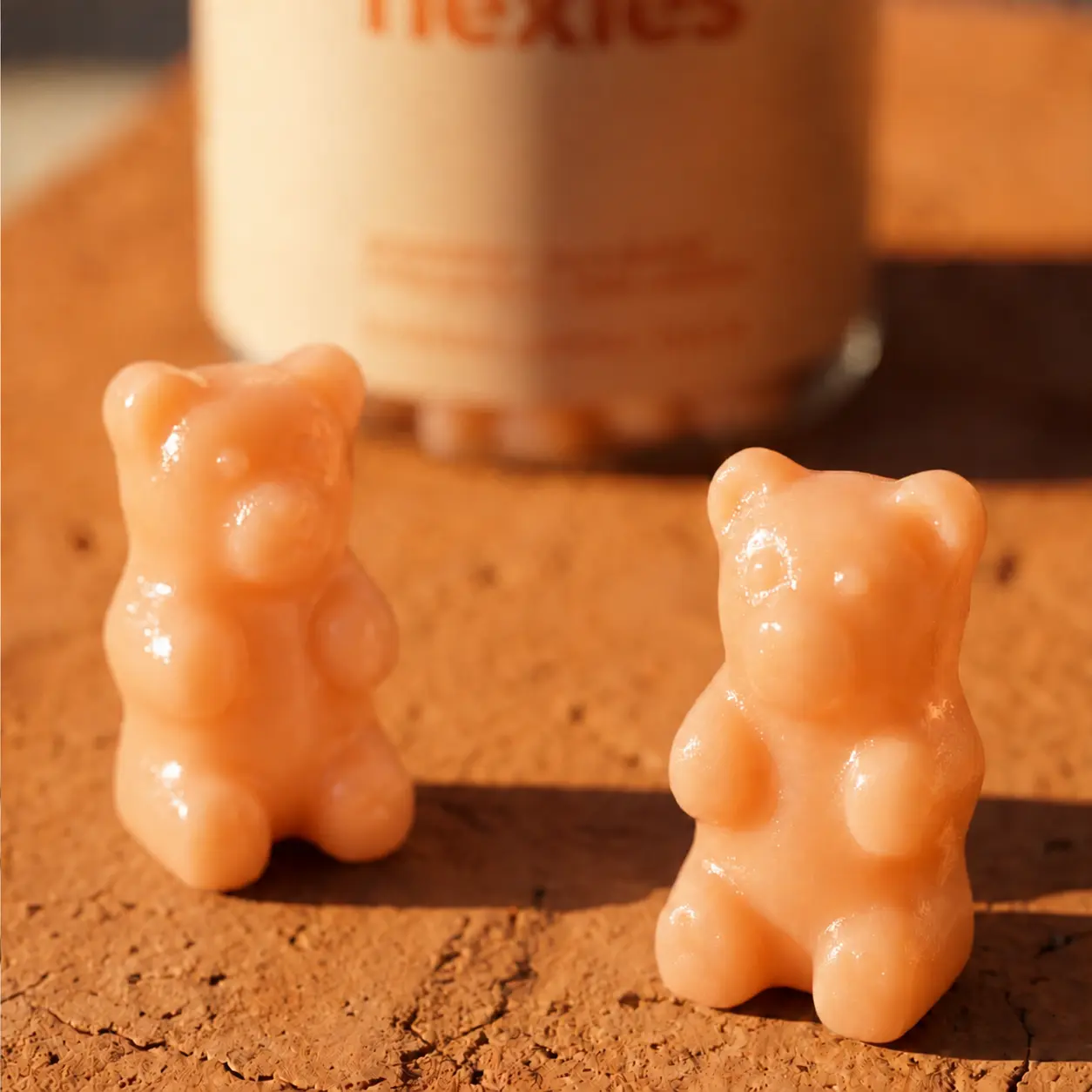 Two Tropical Orange bear-shaped gummies beside a Sun Kissed bottle