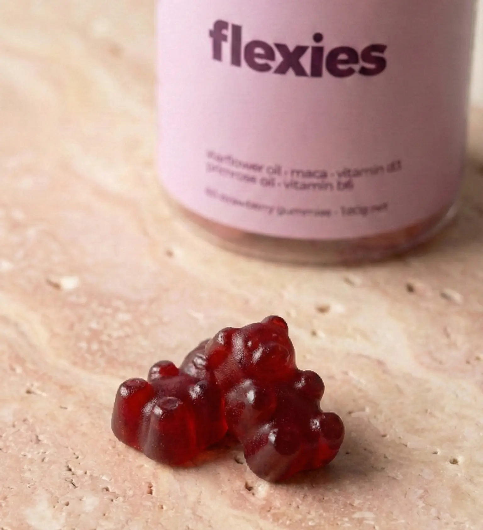 Close-up of cranberry PMS relief gummies with bottle in background